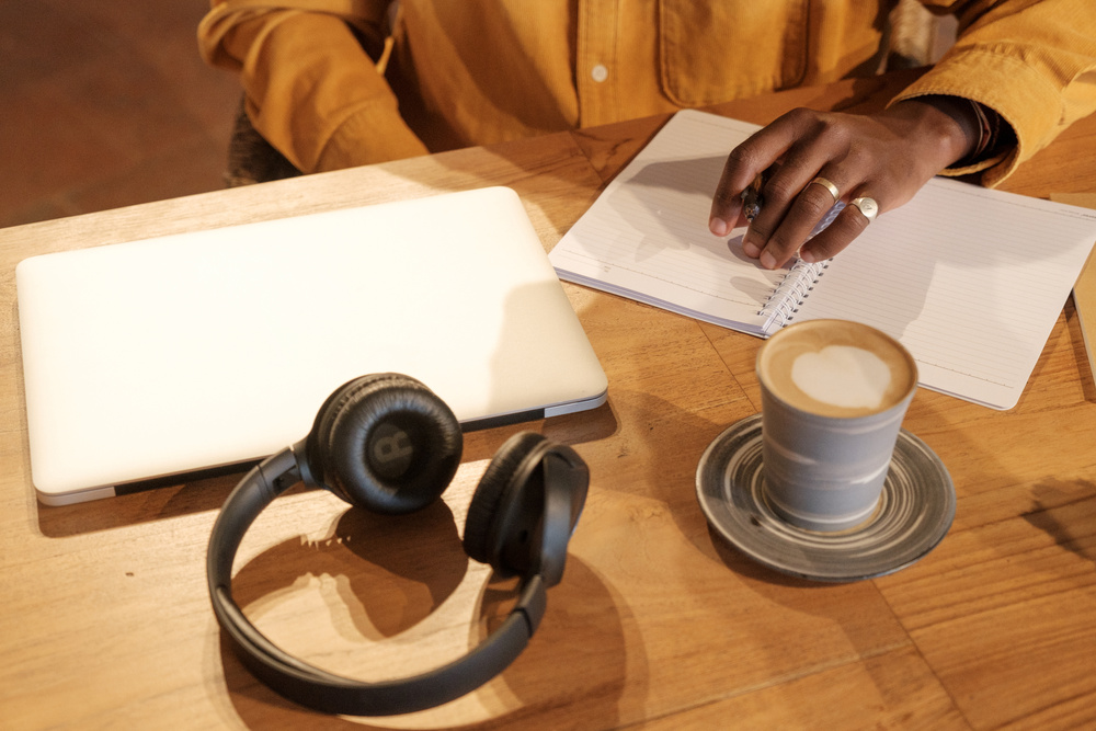 Podcaster with Notebook, Laptop, Headphones, and Coffee